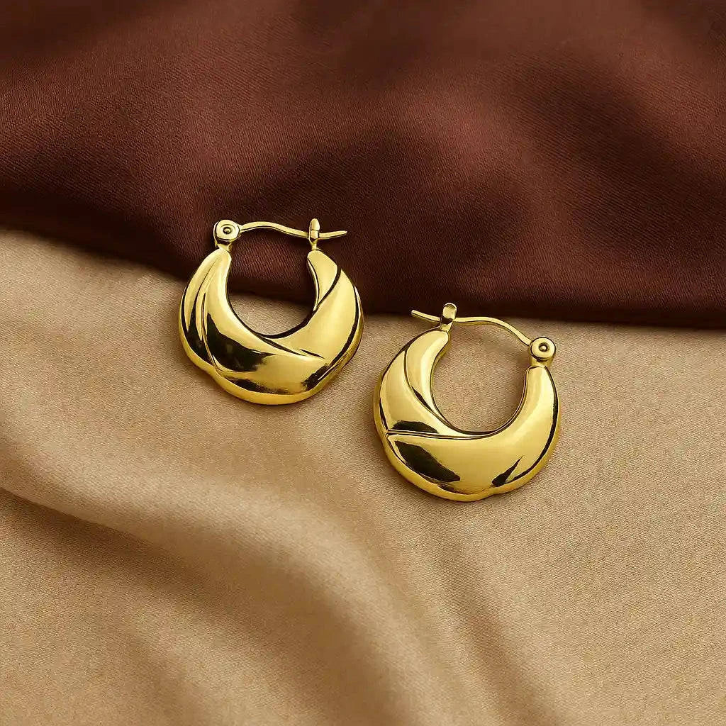 Gold hoop earrings on a brown fabric background