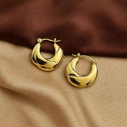 Gold hoop earrings on a brown fabric background