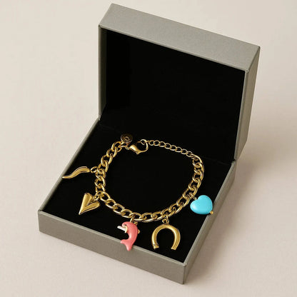 Gold bracelet with charms in a gray box on a beige background