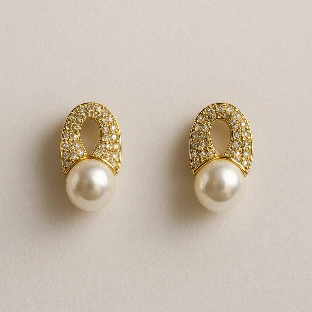 Pair of gold earrings with pearls on a light beige background