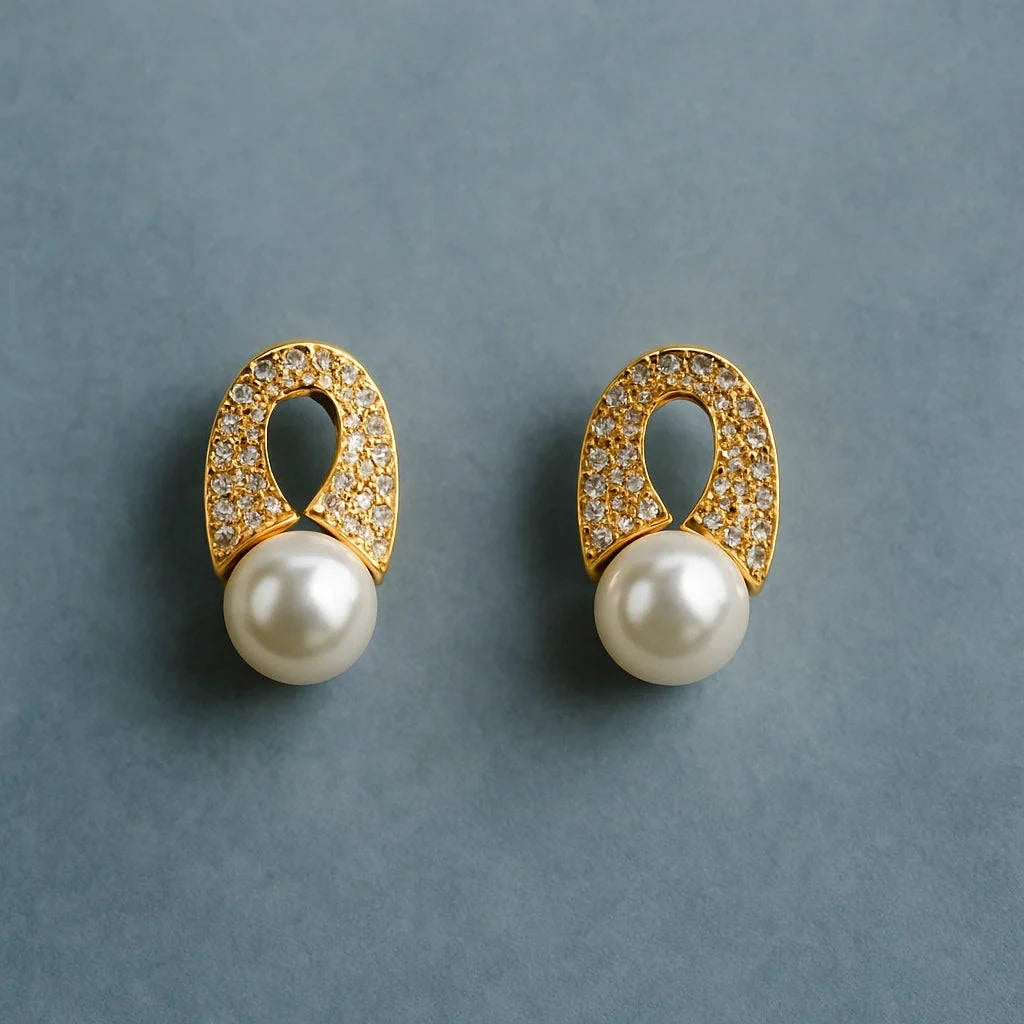Pair of gold earrings with pearl centers on a gray background