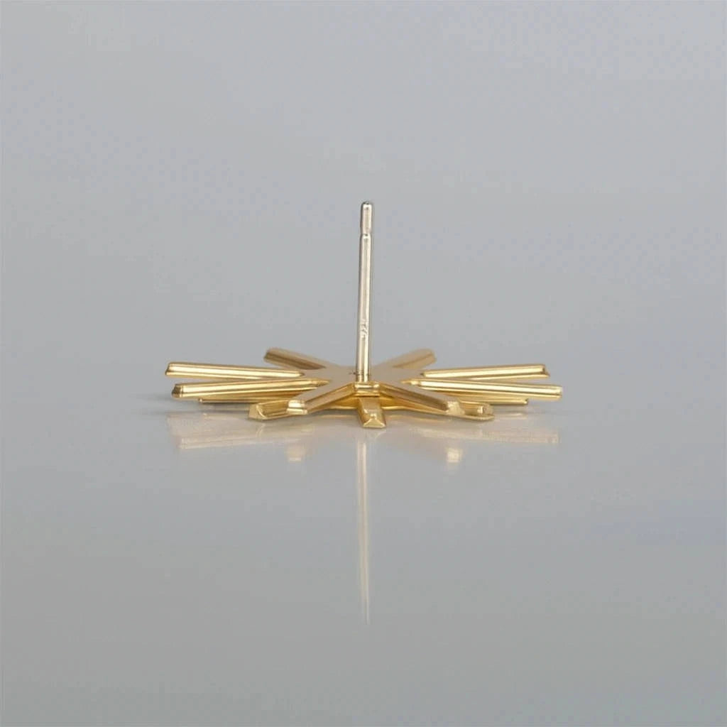 Gold geometric earrings on a gray background