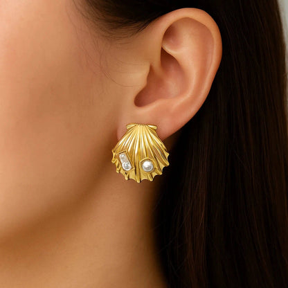 Gold shell-shaped earring with embedded pearls worn by a person.