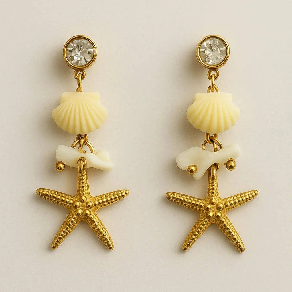 Pair of earrings with starfish, shell, and crystal elements on a beige background