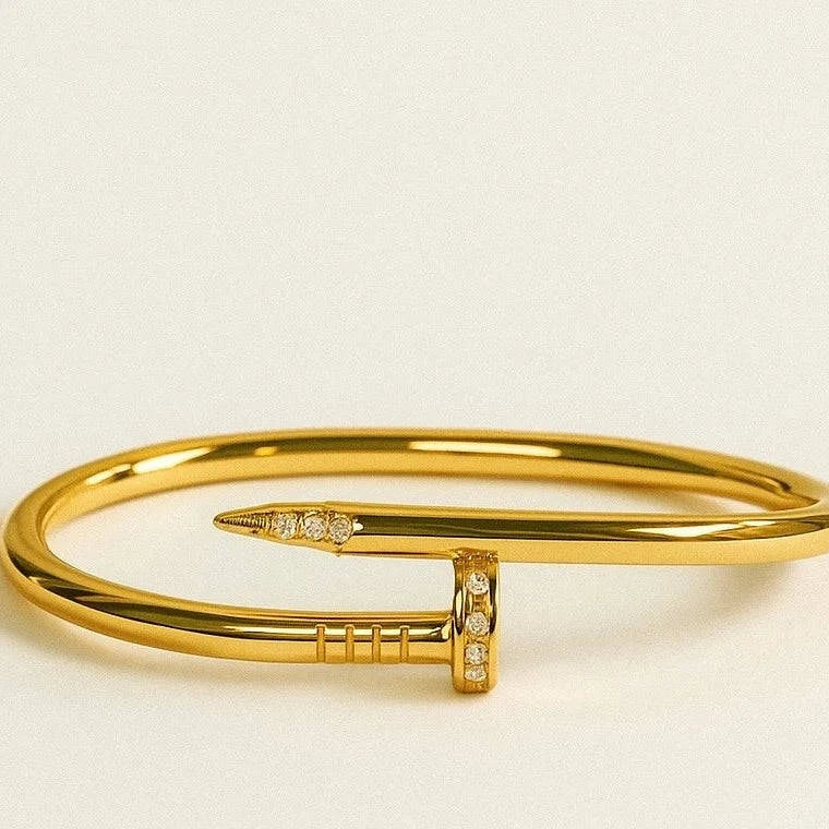 Gold bracelet with a decorative clasp on a beige background