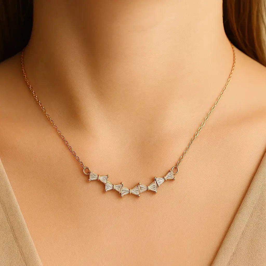 Gold necklace with diamond-like stones on a model wearing a beige top.