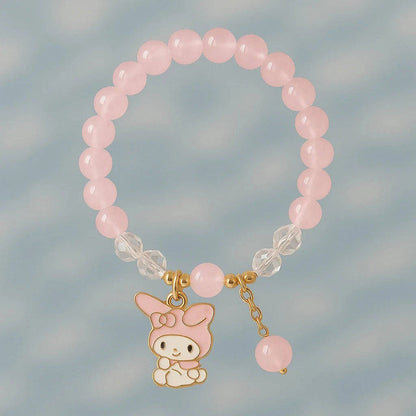 Pink beaded bracelet with a small cartoon character charm on a light blue background