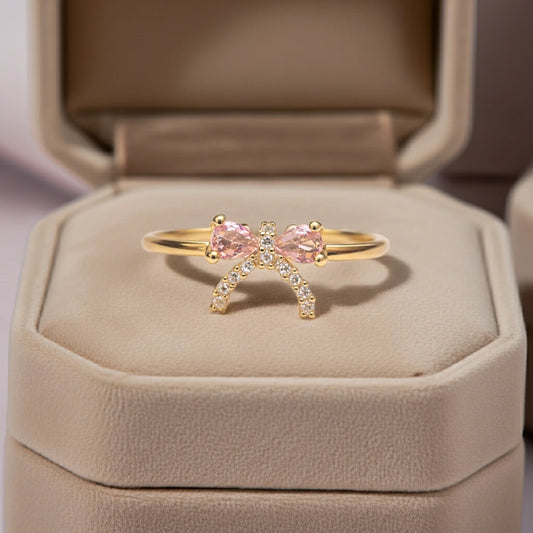 Gold ring with pink gemstones in a beige jewelry box