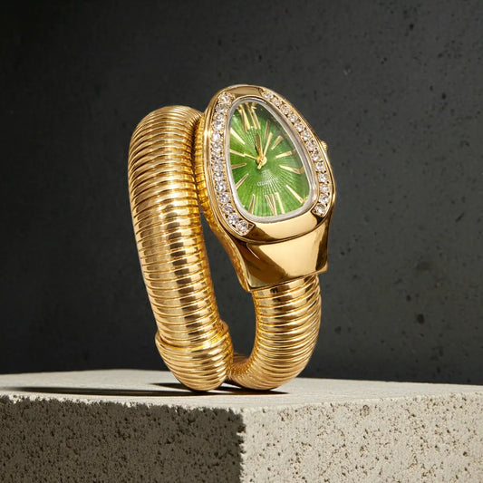 Gold watch with green face on a concrete surface against a dark background