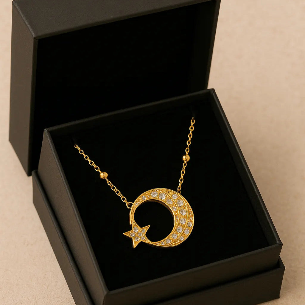 Gold necklace with a crescent moon and star pendant in an open black jewelry box on a beige background