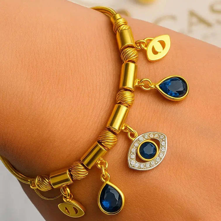 Gold bracelet with blue gemstones on a wrist against a light background