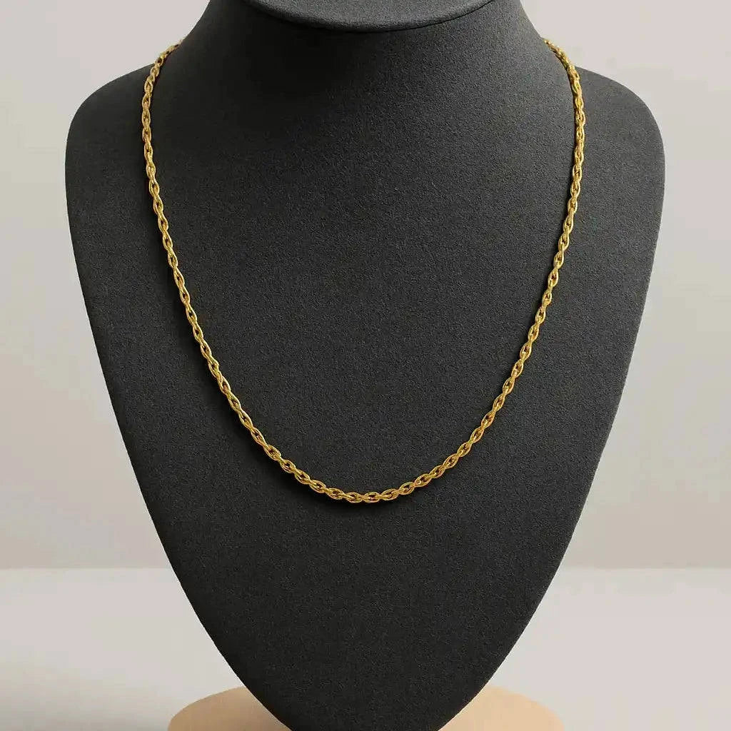Gold chain necklace on a black mannequin bust with a gray background