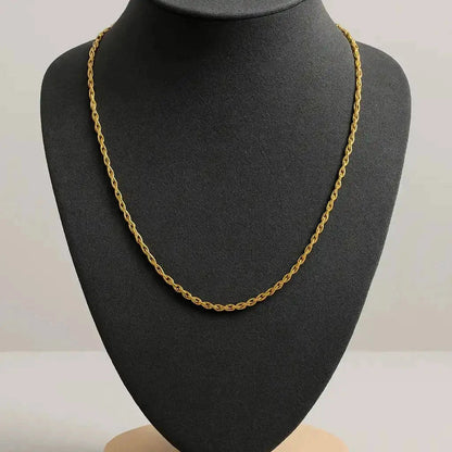 Gold chain necklace on a black mannequin bust with a gray background